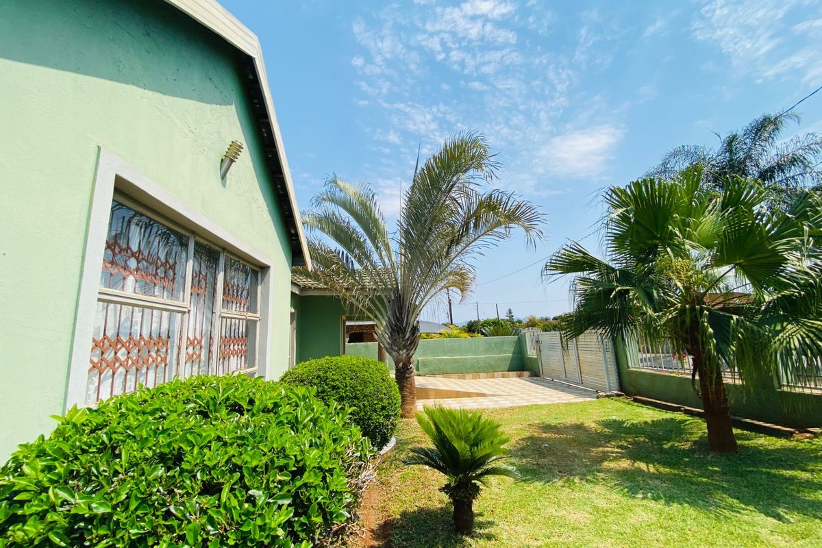 A well-maintained rear garden featuring a paved patio area, established landscaping, and secure boundary walls with integrated security gates.