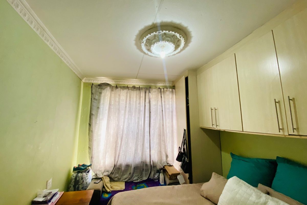 A bedroom featuring built-in cupboards, decorative ceiling rose, and cornice detailing.