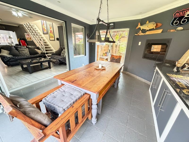 Enclosed patio area featuring a built-in braai, tiled flooring, and direct access to the adjacent living space through large sliding doors.