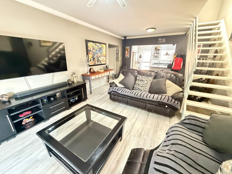 Open plan living area featuring light laminate flooring, a wood burning stove, and a staircase leading to the upper level.