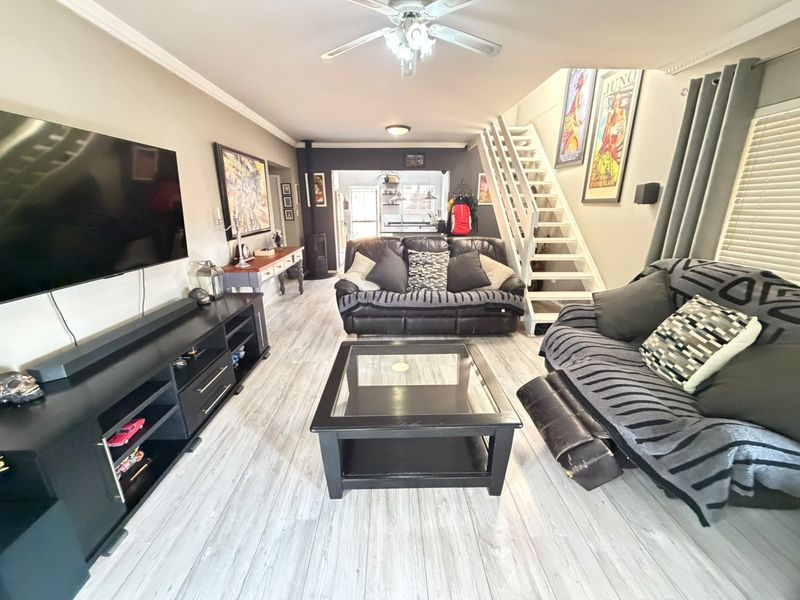 Open plan living area featuring light laminate flooring, a wood-burning stove, and a staircase leading to the upper level.