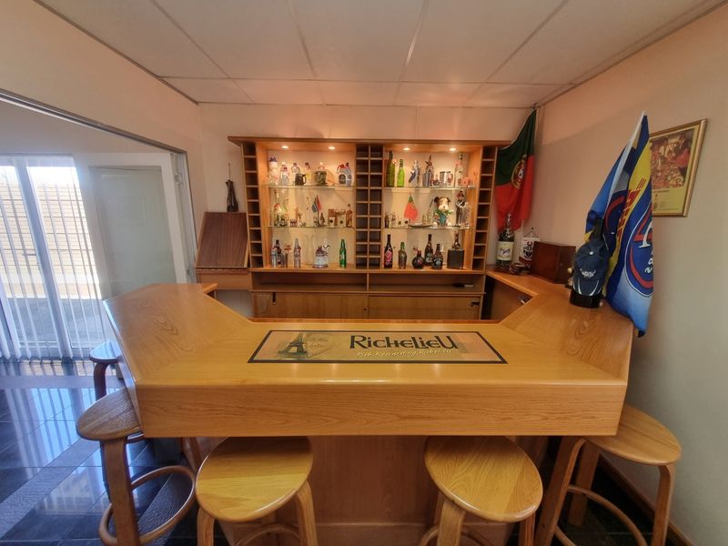 A dedicated bar area featuring a custom-built wooden counter and integrated display shelving with built-in lighting.