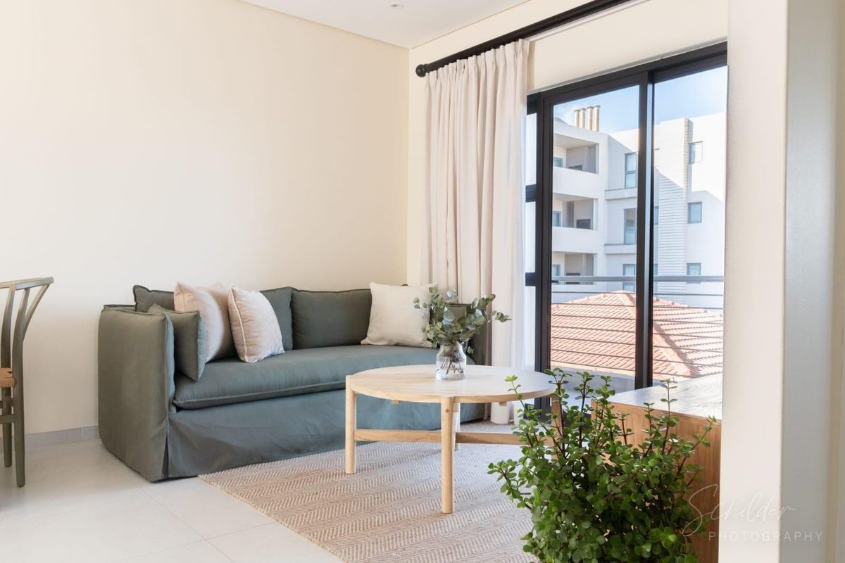 A bright living room featuring tiled flooring and a large sliding glass door that provides access to an outdoor area.