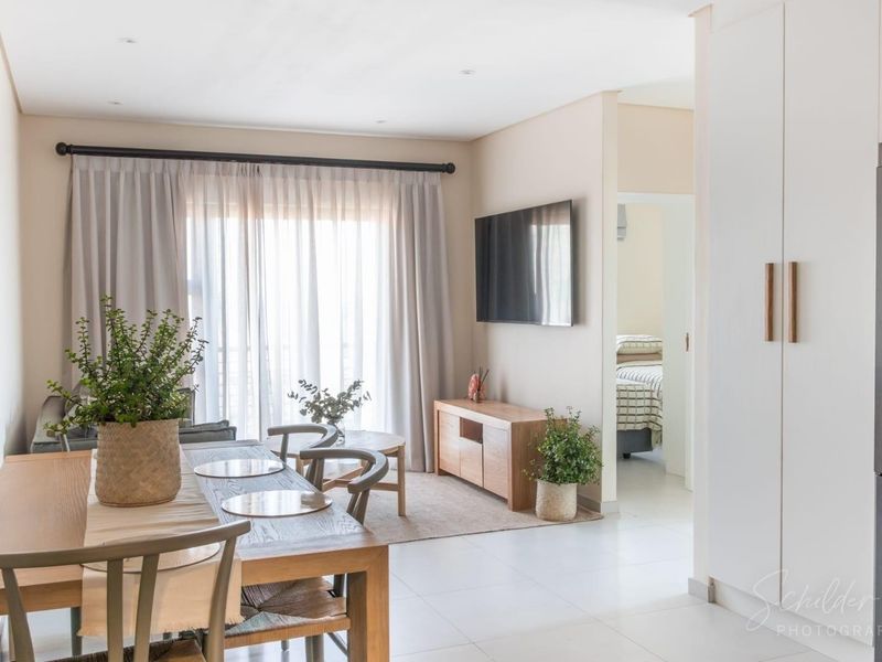 Bright open-plan living and dining area featuring neutral tiled flooring, recessed lighting, and seamless access to adjacent rooms.