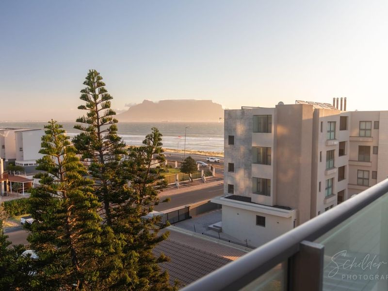 Elevated view overlooking the coastline and Table Mountain, captured from a balcony with a modern glass balustrade.