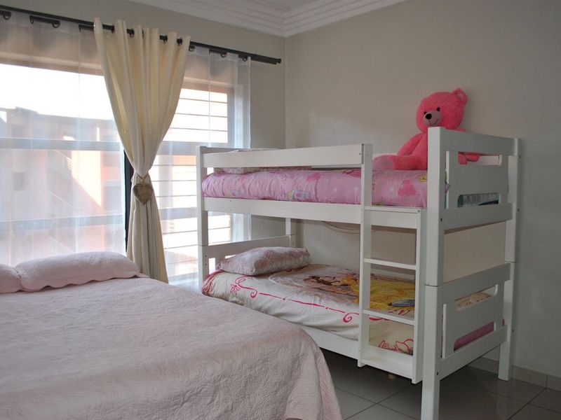 A bedroom featuring tiled flooring, a large window with natural light, and decorative ceiling cornicing.