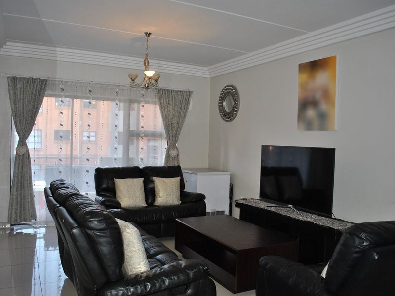 A living room featuring tiled flooring, crown molding, and a sliding glass door providing access to the balcony.