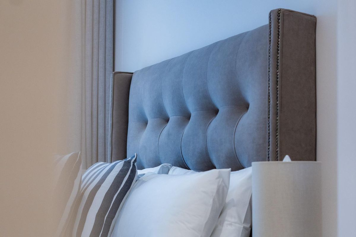 A close-up view of a bedroom featuring a tufted upholstered headboard.