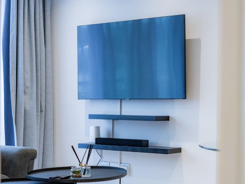A modern living room wall featuring mounted shelving and a television setup with clean finishes.