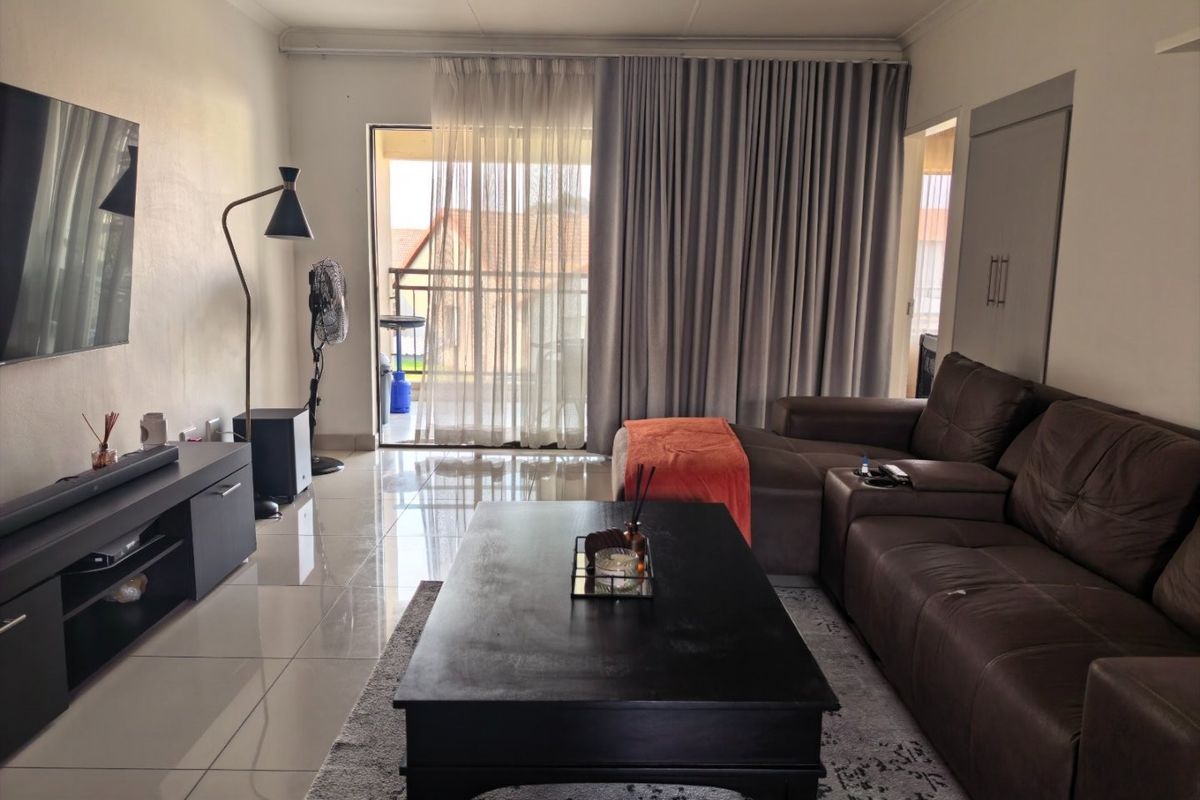 A living room featuring tiled flooring, a sliding glass door leading to a balcony, and a built-in cupboard.