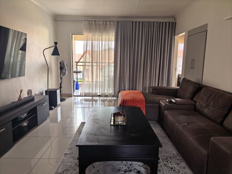 A living room featuring tiled flooring, a sliding glass door leading to a balcony, and a built-in cupboard.