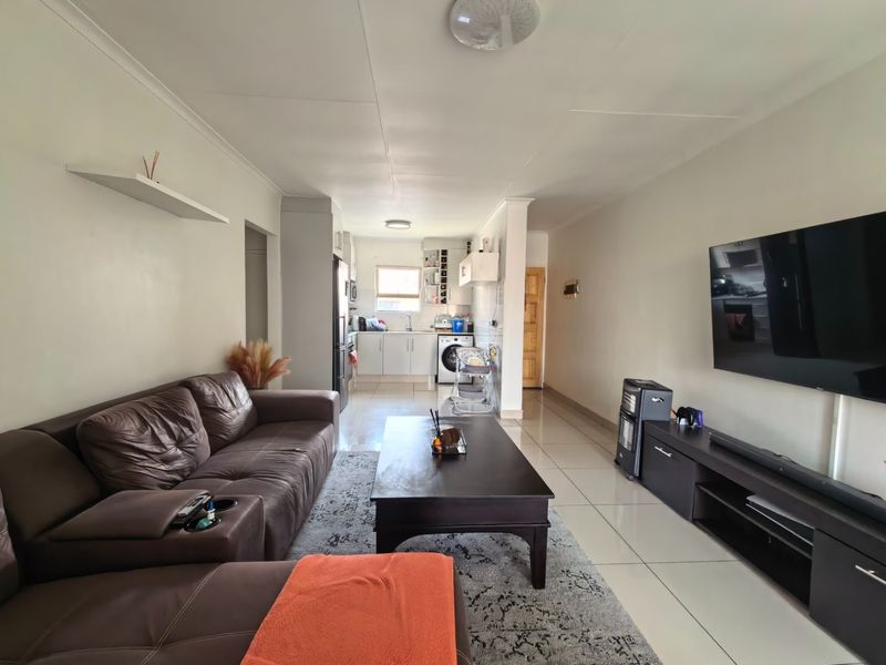 Open-plan living area featuring tiled flooring and a functional kitchen space with built-in cabinetry and laundry connections.