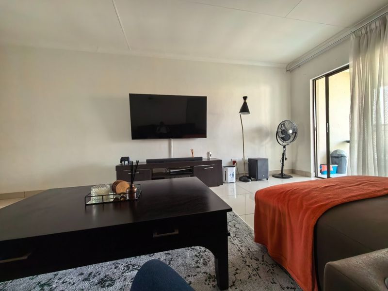 A bright living room featuring tiled flooring and a sliding glass door providing access to an outdoor area.
