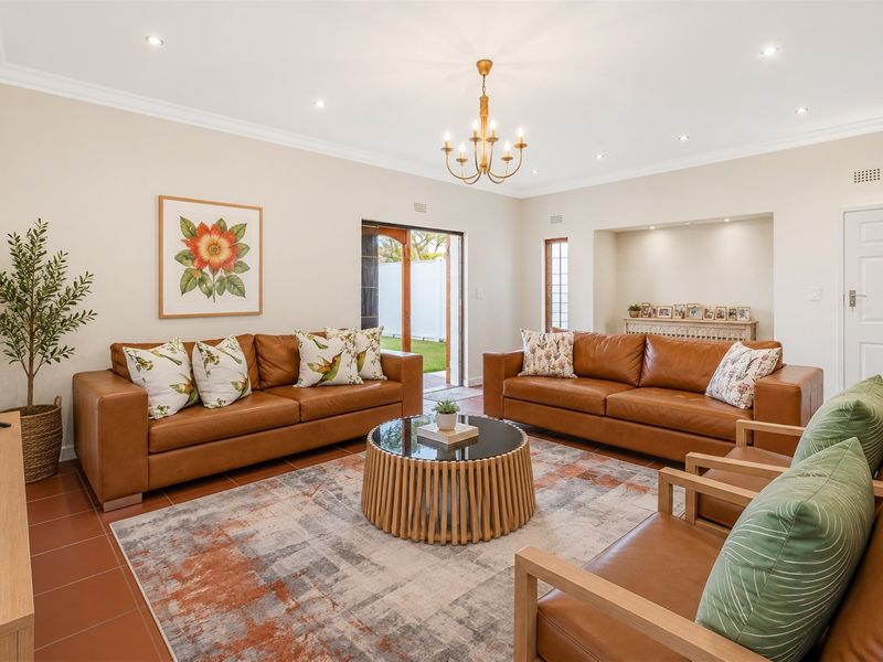 Spacious living room featuring tiled flooring, recessed downlights, a decorative chandelier, and a built-in alcove with direct access to the outdoor area.
