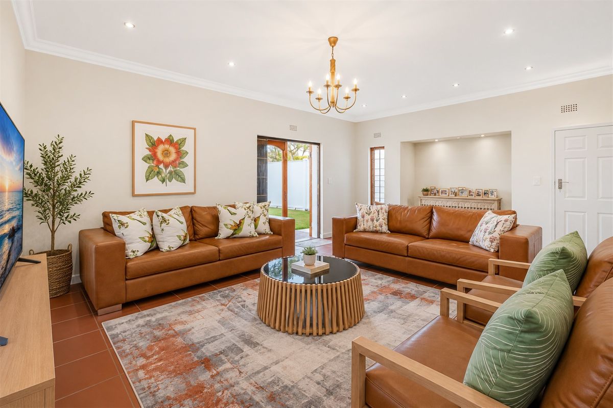 Spacious living room featuring tiled flooring, recessed downlights, a decorative chandelier, and a built-in alcove with direct access to the outdoor area.