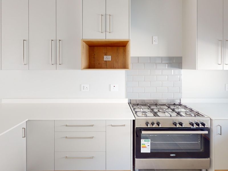 Modern kitchen featuring light grey cabinetry, stone countertops, a subway tile backsplash, and a stainless steel gas stove with oven.
