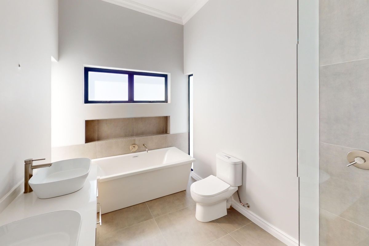 Modern bathroom featuring a freestanding bathtub, dual vessel sinks, a built-in wall niche, and a glass-enclosed shower with neutral tile finishes.
