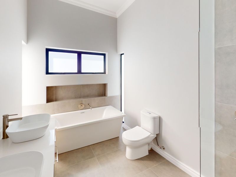 Modern bathroom featuring a freestanding bathtub, dual vessel sinks, a built-in wall niche, and a glass-enclosed shower with neutral tile finishes.