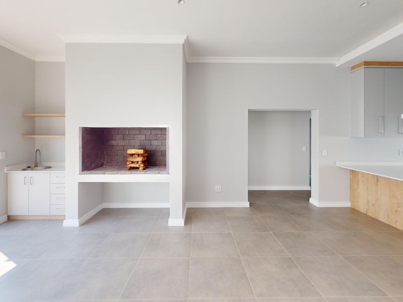 Spacious open-plan living area featuring a built-in fireplace, modern kitchen cabinetry with an island, and neutral tiled flooring throughout.