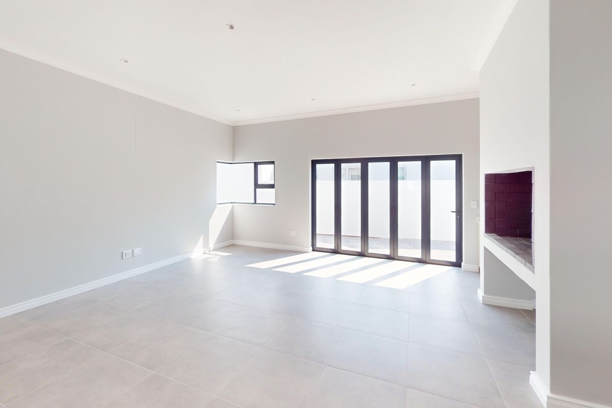 Spacious, light-filled living area featuring neutral tiled flooring, a built-in fireplace, and modern aluminium stacker doors opening to the exterior.