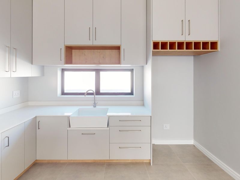 Modern kitchen featuring light grey cabinetry, quartz countertops, an apron-front sink, and integrated oven with gas hob.