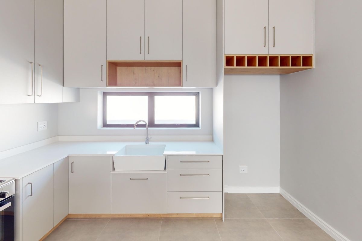 Modern kitchen featuring light grey cabinetry, quartz countertops, an apron-front sink, and integrated oven with gas hob.
