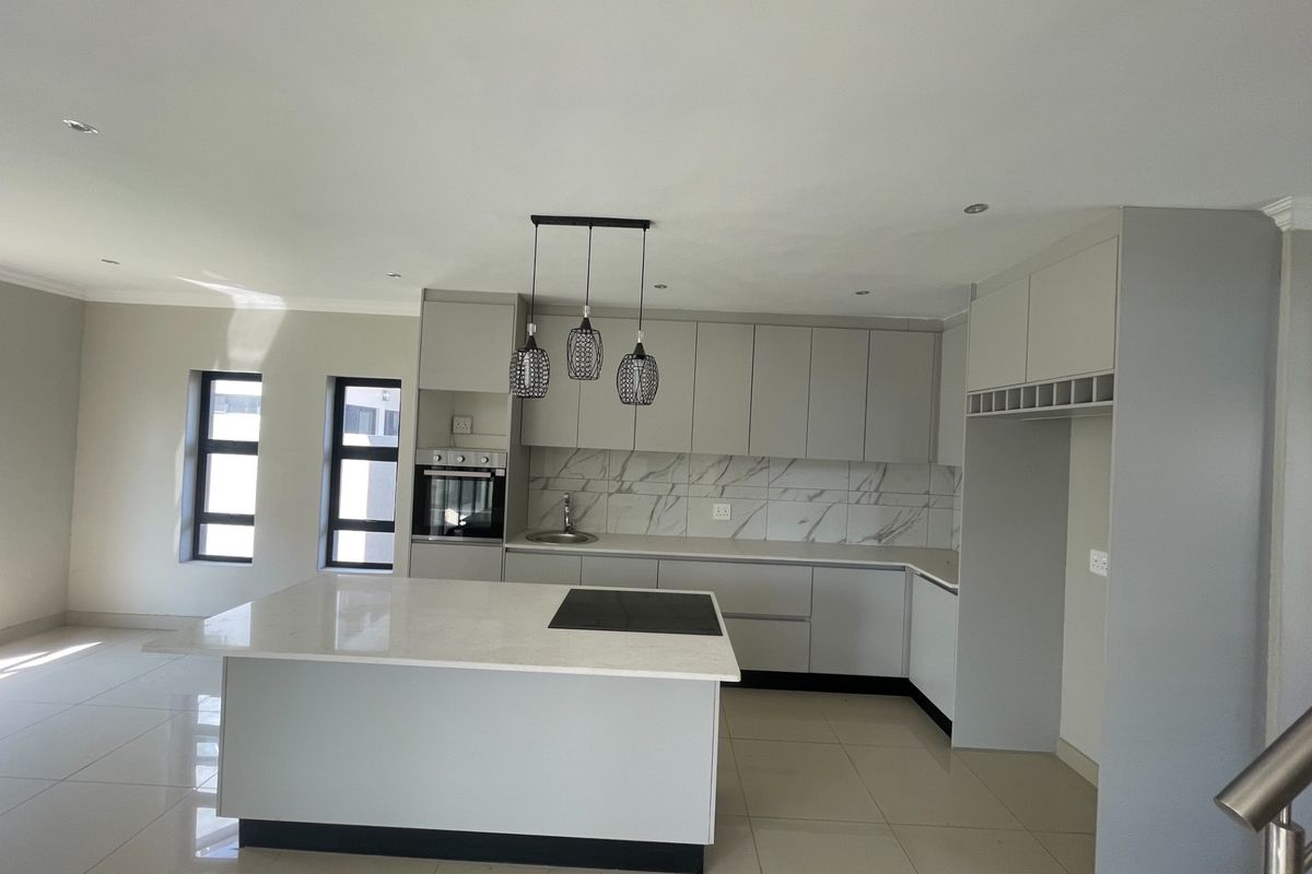 Modern kitchen featuring a central island, built-in oven, cooktop, marble-look backsplash, and ample cabinetry in a clean, open-plan layout.