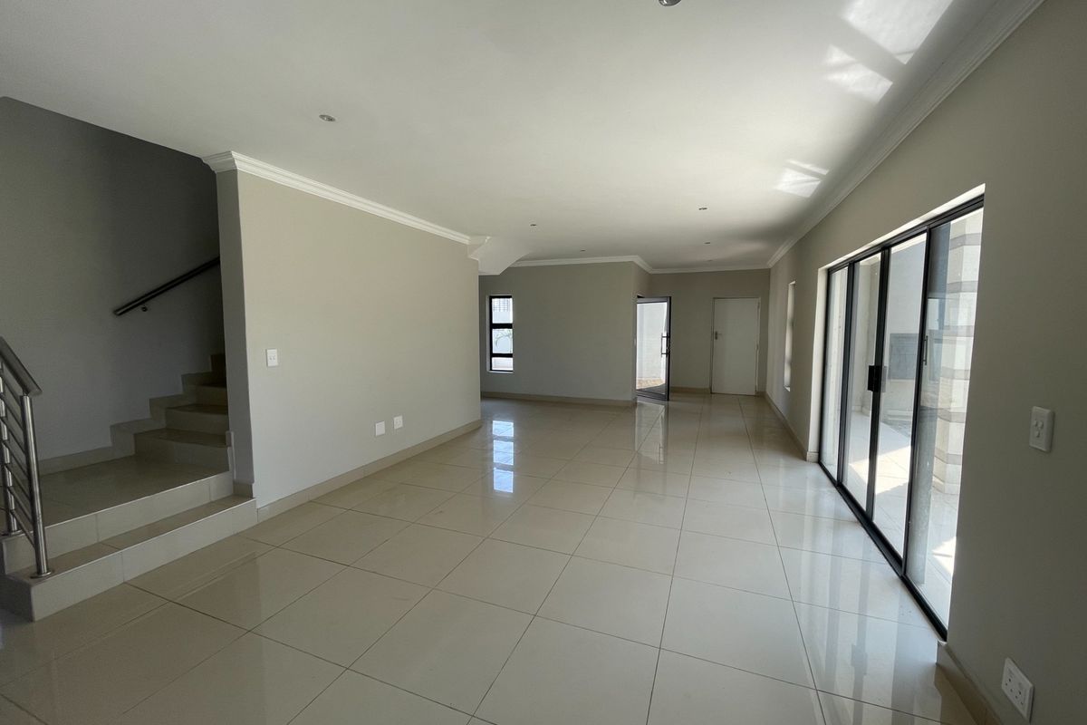 Spacious, open-plan living area featuring neutral tiled flooring, recessed lighting, and large sliding glass doors providing access to the exterior.