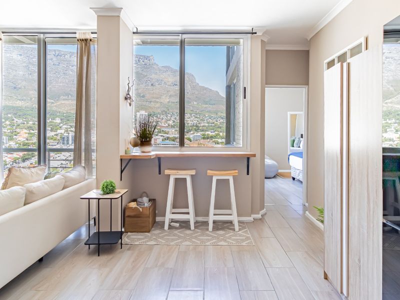 Bright open-plan living area featuring large windows with mountain views, a built-in breakfast bar, and modern tiled flooring.
