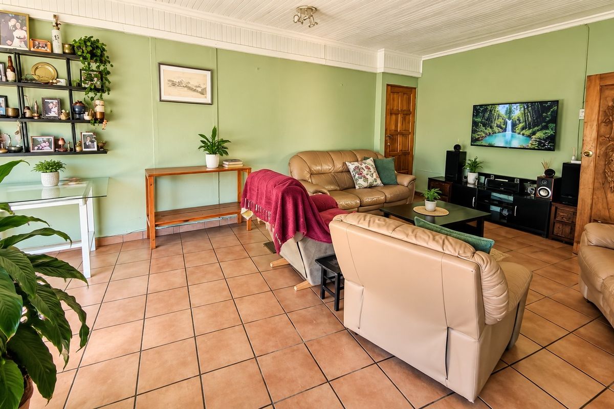 A spacious living room featuring terracotta tiled flooring, a timber panelled ceiling, and a decorative carved wooden door.