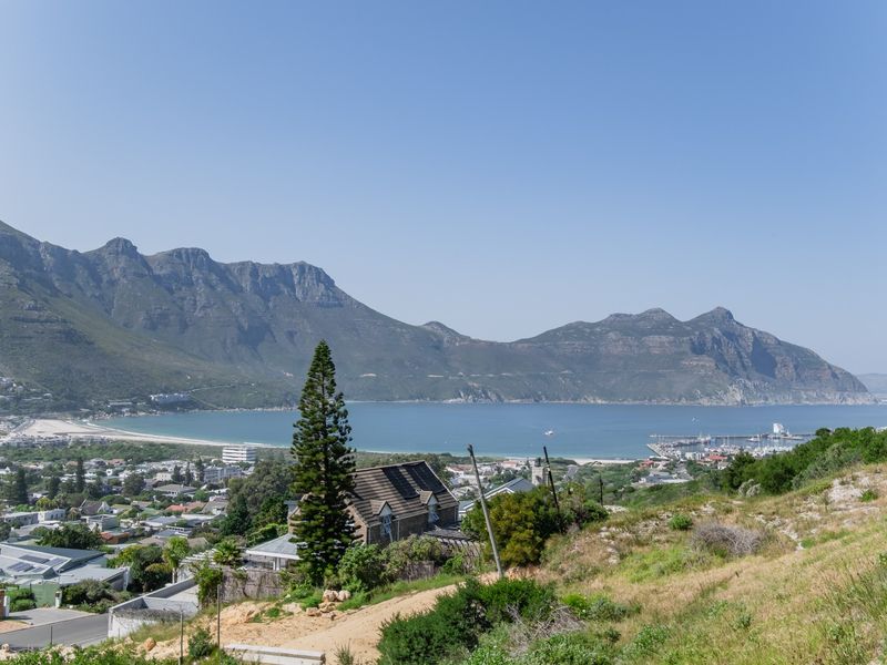 A scenic elevated view overlooking the coastal town, bay, and surrounding mountain range.