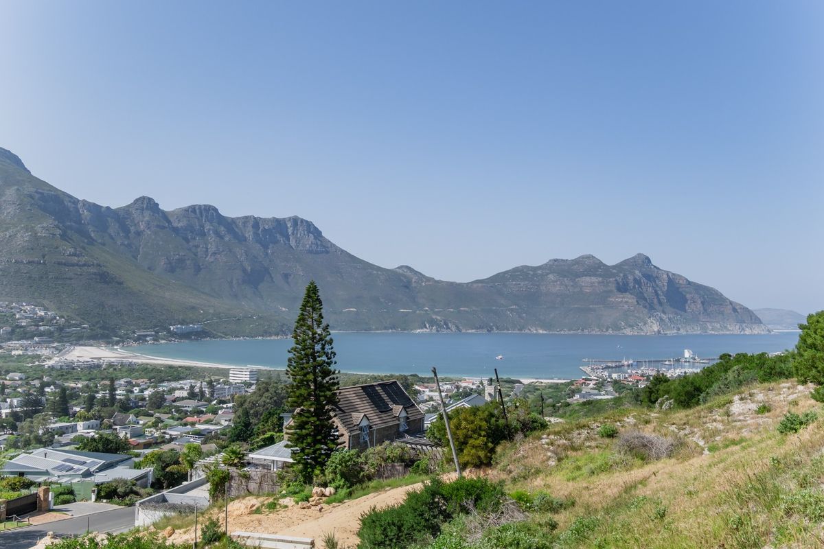 A scenic elevated view overlooking the coastal town, bay, and surrounding mountain range.