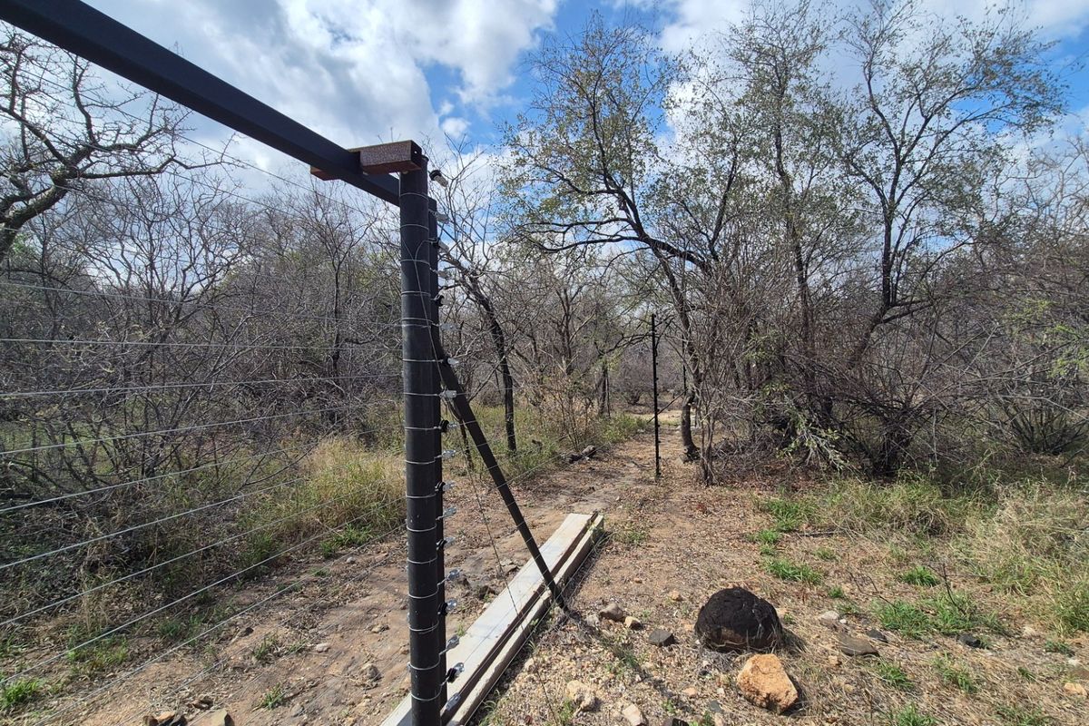 A view of the property boundary featuring installed electric fencing and a cleared perimeter path through natural bushveld vegetation.