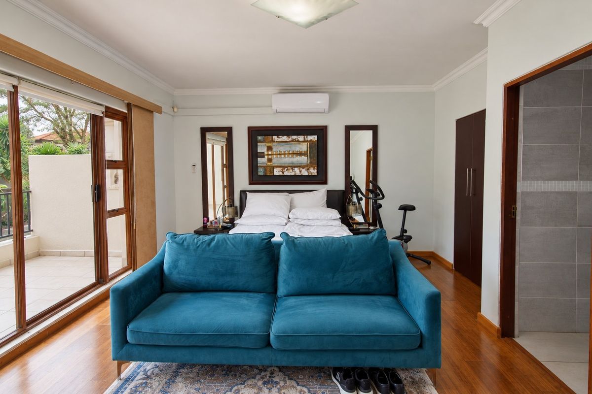 Spacious bedroom featuring hardwood flooring, built-in cupboards, split-system air conditioning, and direct access to a private balcony and en-suite bathroom.
