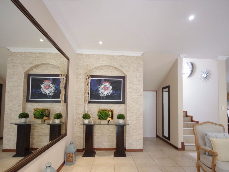 A welcoming entrance hall featuring tiled flooring, recessed wall niches with decorative stonework, and a staircase leading to the upper level.