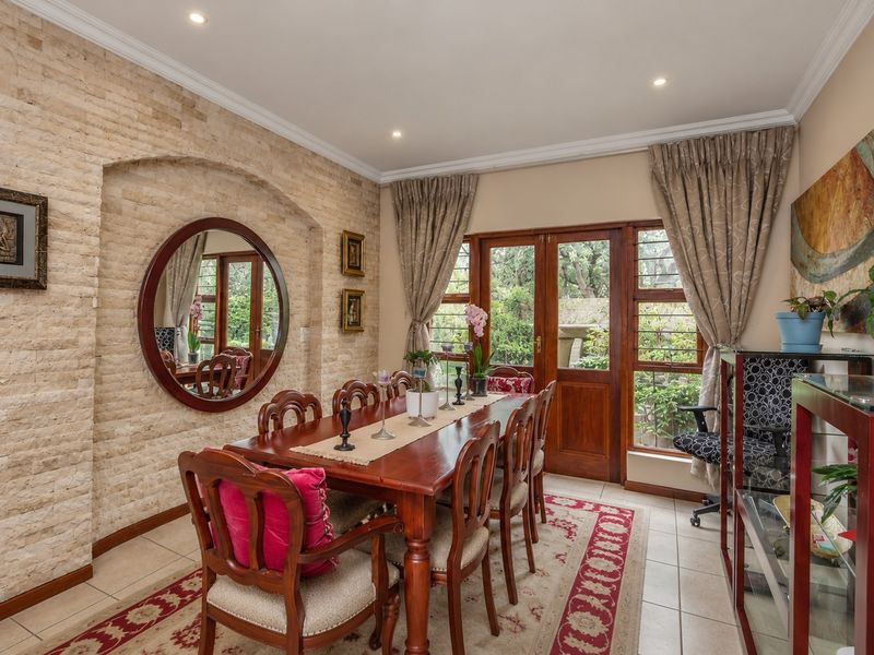 Dining room featuring a textured stone cladding feature wall, tiled flooring, and direct access to the garden through wooden framed glass doors.