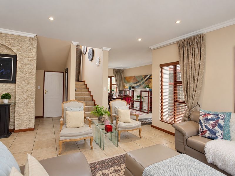 Spacious living area featuring tiled flooring, a stone accent wall, and a staircase leading to the upper level with neutral finishes throughout.