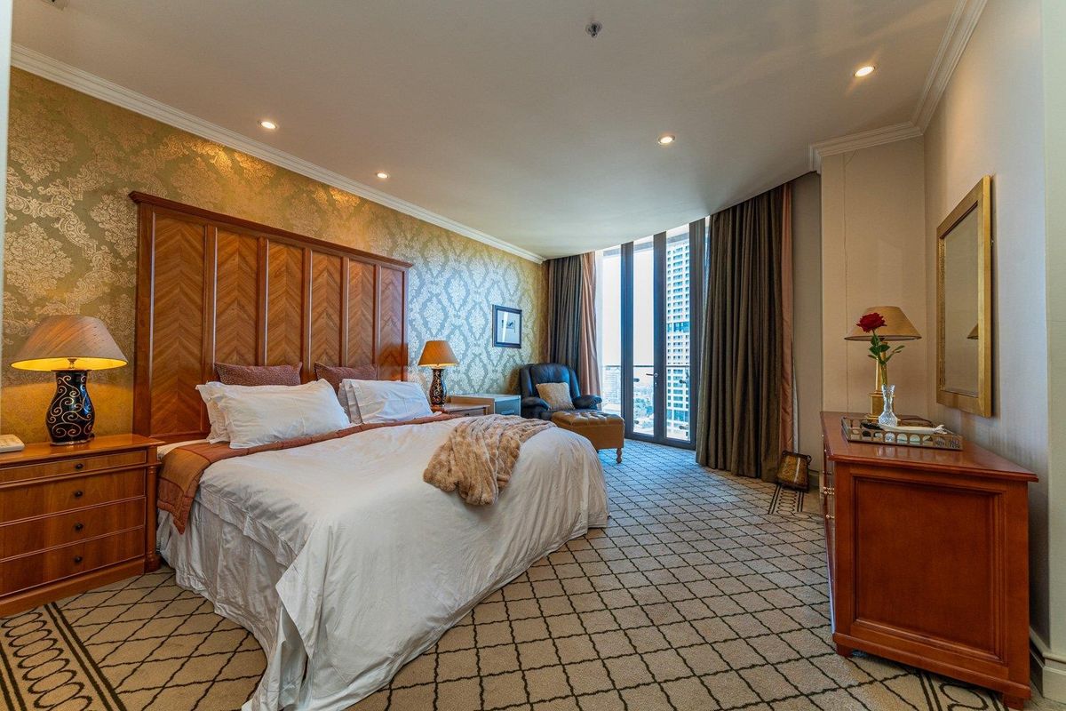 Spacious bedroom featuring patterned carpeting, recessed lighting, and floor-to-ceiling windows with direct access to a private balcony.