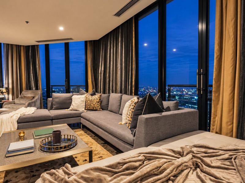 Modern living room featuring floor-to-ceiling windows with expansive city views, recessed lighting, and integrated ducted air conditioning.