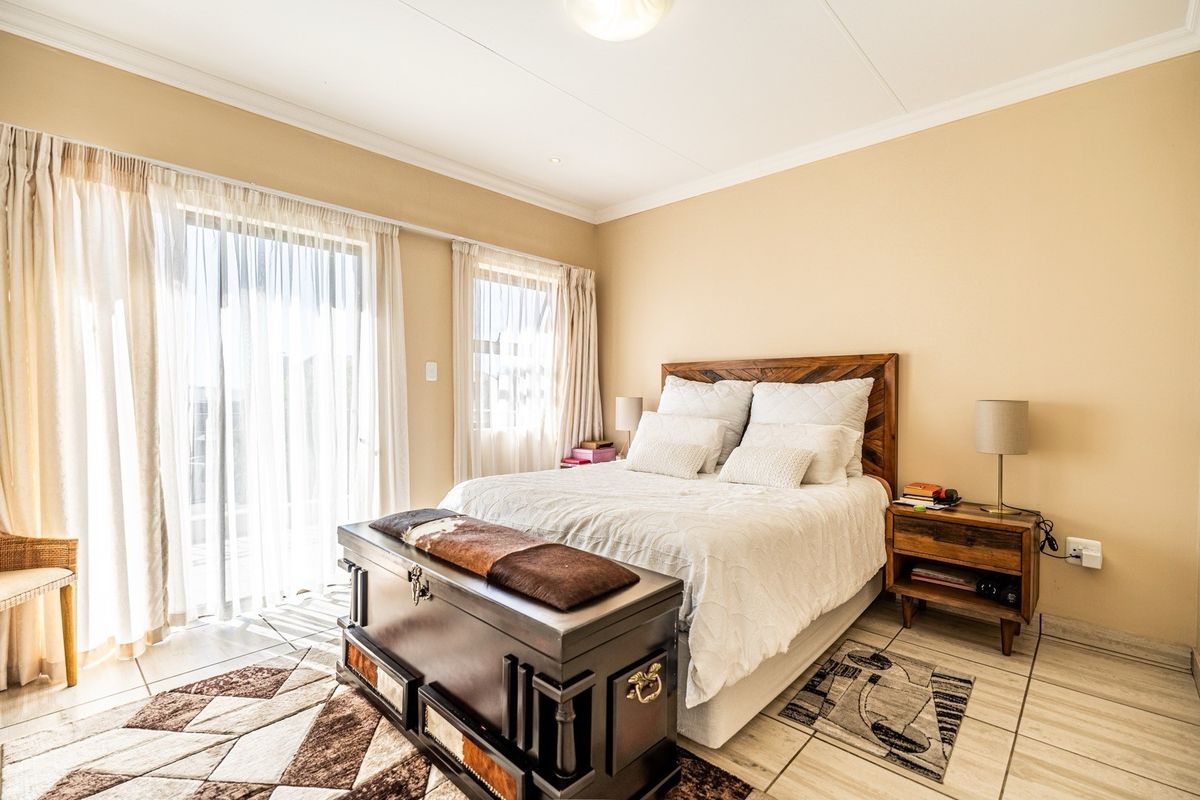 A well-lit bedroom featuring tiled flooring, coved ceilings, and a sliding glass door providing access to the exterior.