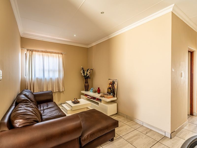 A living room featuring tiled flooring, recessed downlighting, and coved ceiling cornices, providing a neutral base for interior design updates.