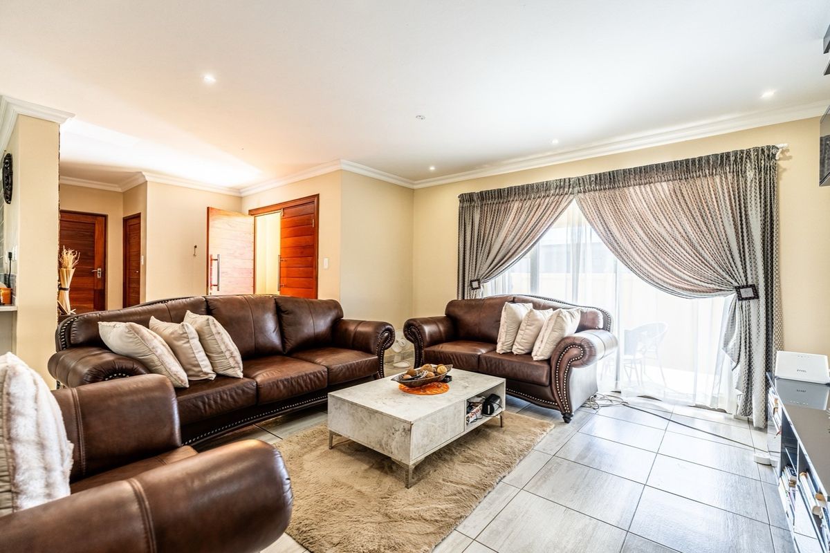 A well-maintained living room featuring tiled flooring, recessed downlighting, and a large sliding glass door providing access to the outdoor area.
