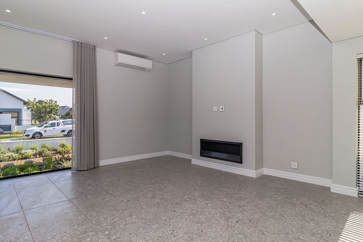 A bright, modern living room featuring large format floor tiles, a built-in fireplace, split-system air conditioning, and direct access to the exterior.