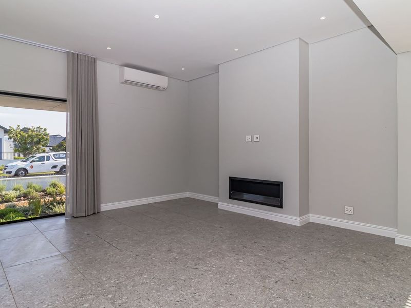 A bright, modern living room featuring large format floor tiles, a built-in fireplace, split-system air conditioning, and direct access to the exterior.