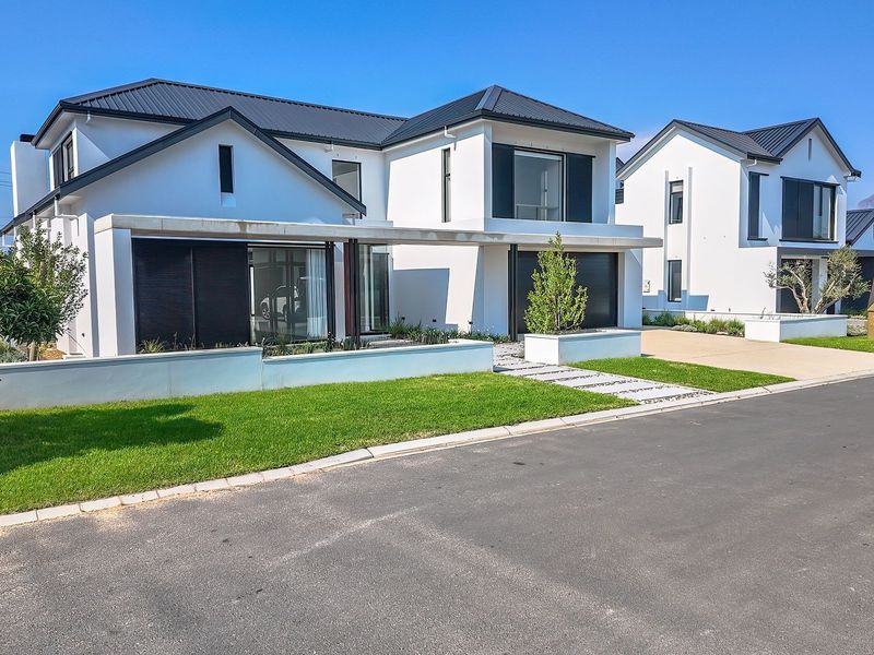 Modern double-story residential home featuring a clean white facade, dark metal roofing, integrated double garage, and well-maintained front garden.
