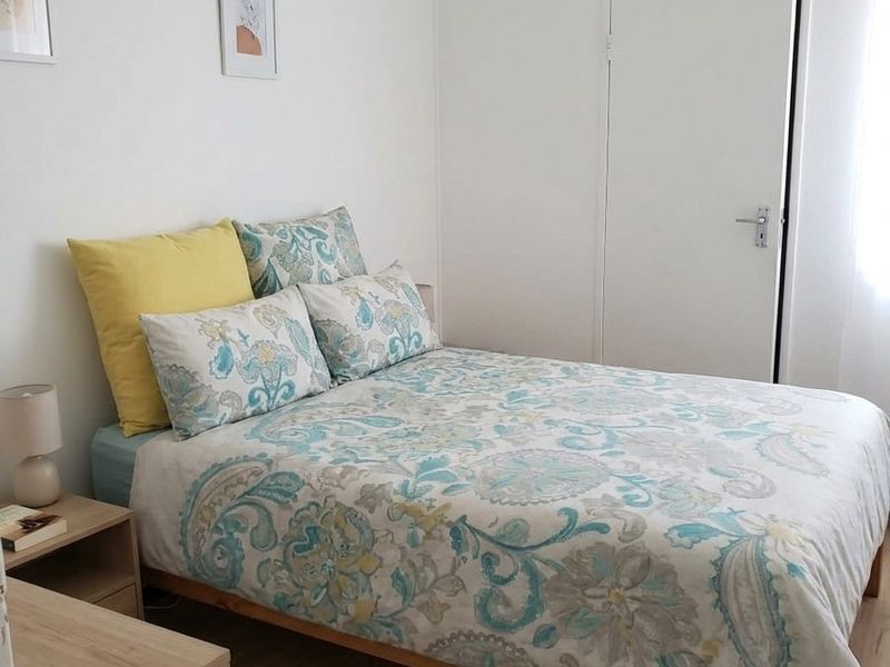 A bright and tidy bedroom featuring light laminate flooring and a functional built-in cupboard for storage.