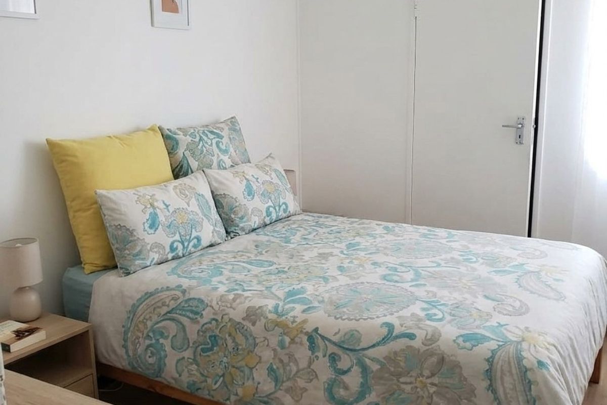 A bright and tidy bedroom featuring light laminate flooring and a functional built-in cupboard for storage.