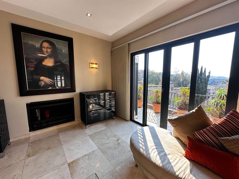 A well-maintained living room featuring stone flooring, a built-in fireplace, and large sliding glass doors that open onto a balcony with outdoor views.