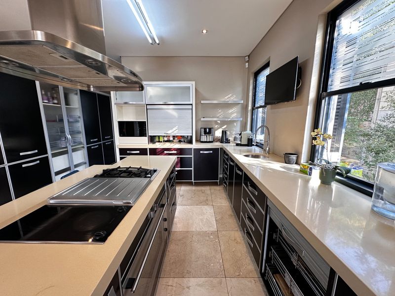 Modern kitchen featuring a central island with gas cooktop, stone countertops, ample built-in cabinetry, and high-quality stainless steel appliances.