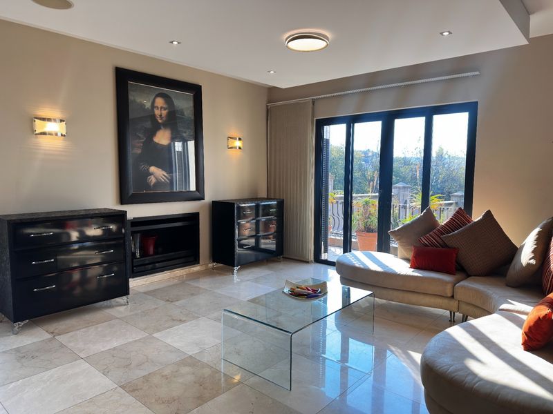 A well-lit living room featuring polished stone tile flooring, a built-in fireplace, and large sliding glass doors that open to an outdoor balcony area.